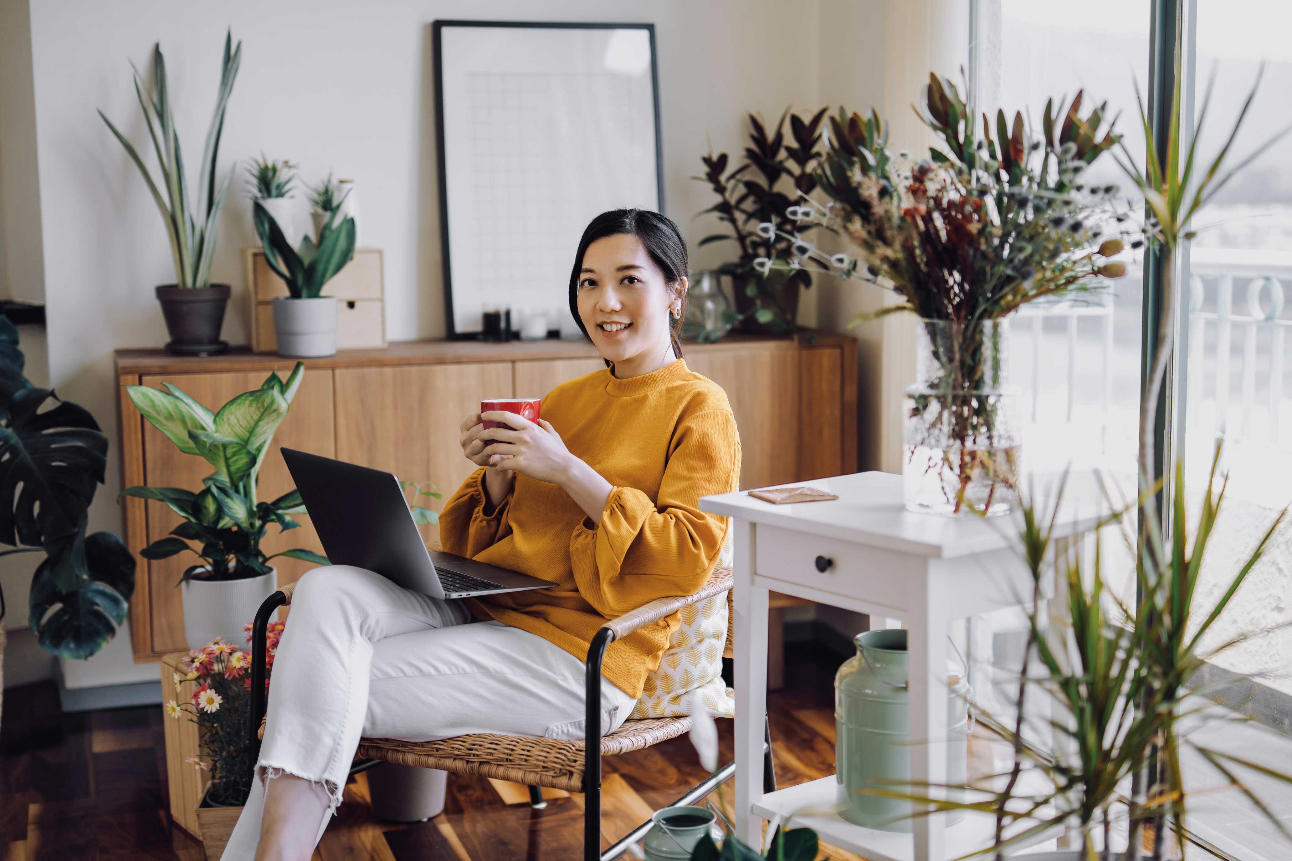 Women wearing yellow shirt holding coffee working on computer